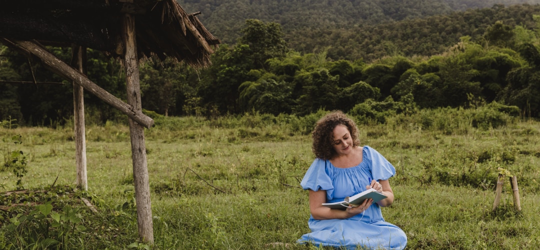 melanie sitting in nature with a notebook